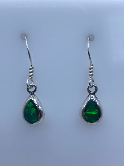 Detalle de un arete mostrando el engaste a mano y el brillo verde del ópalo