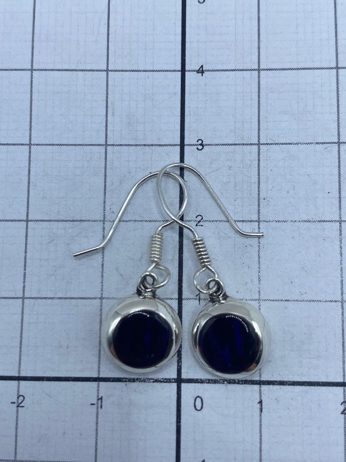 Aretes sobre fondo blanco con gancho de plata visible