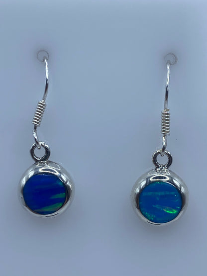 Detalle del engaste de Ópalo de Fuego azul en plata pura, vista frontal de los dos aretes