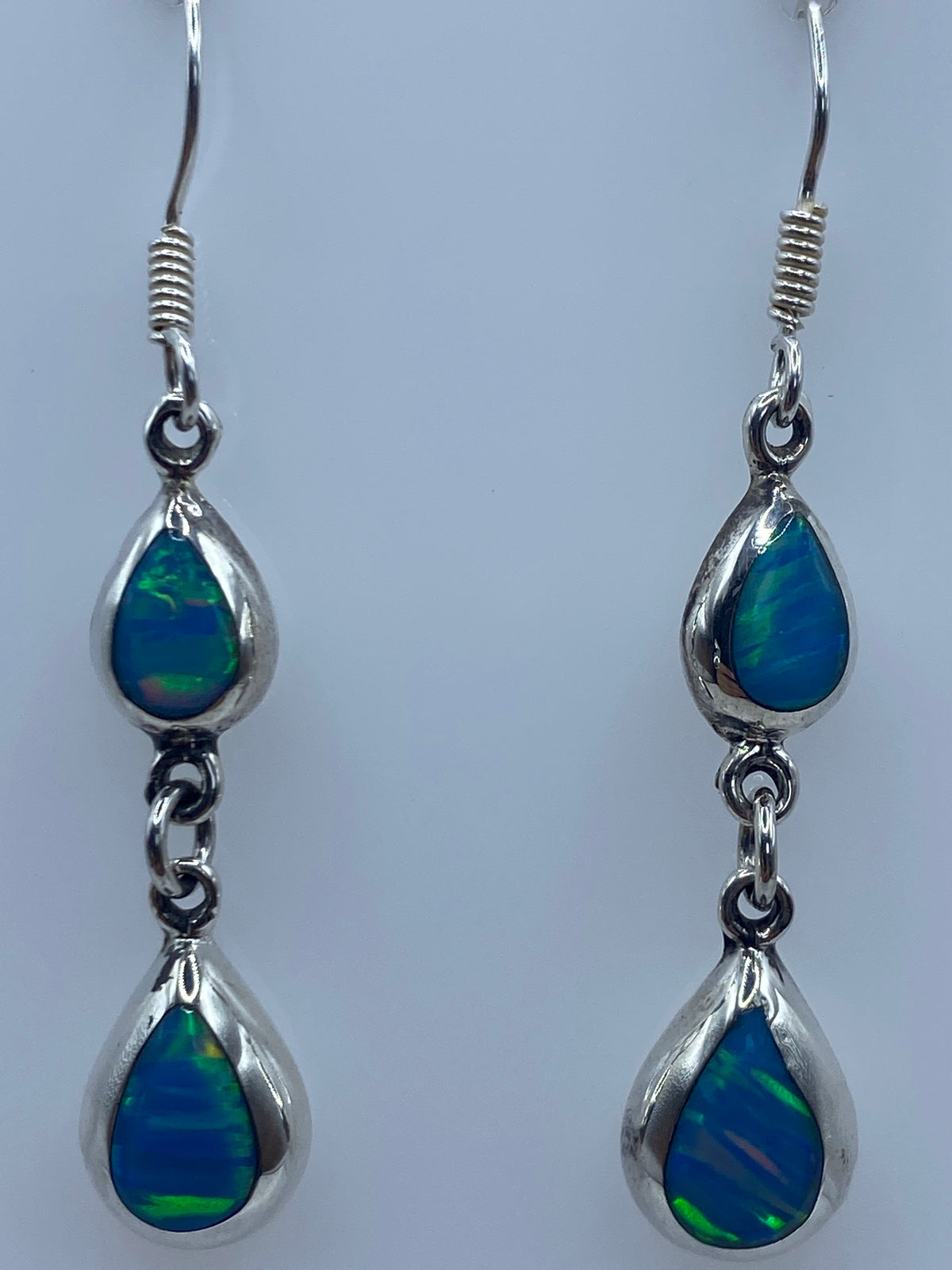 Aretes colgando mostrando el reflejo azul verdoso del ópalo