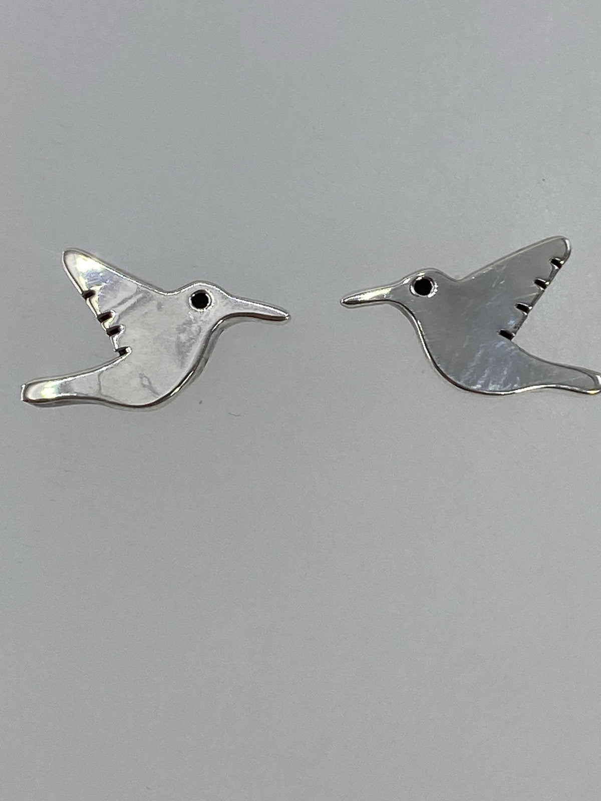 Aretes de cartoneado de plata sobre una mano, mostrando ligereza y detalle