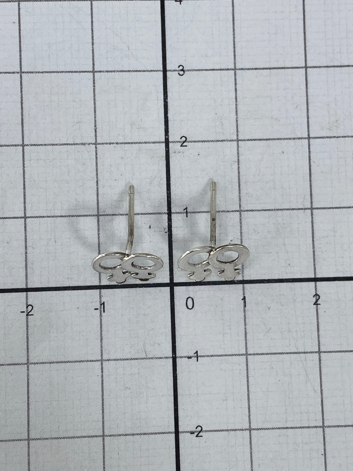 Aretes sobre fondo blanco con escala de medidas
