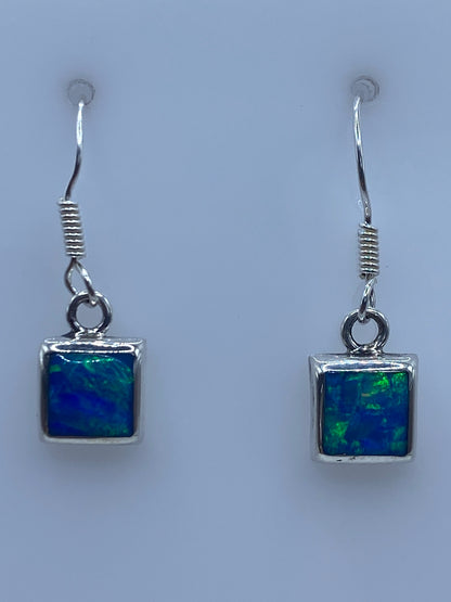 Par de aretes de plata 950 con ópalo de fuego azul, vistos de frente