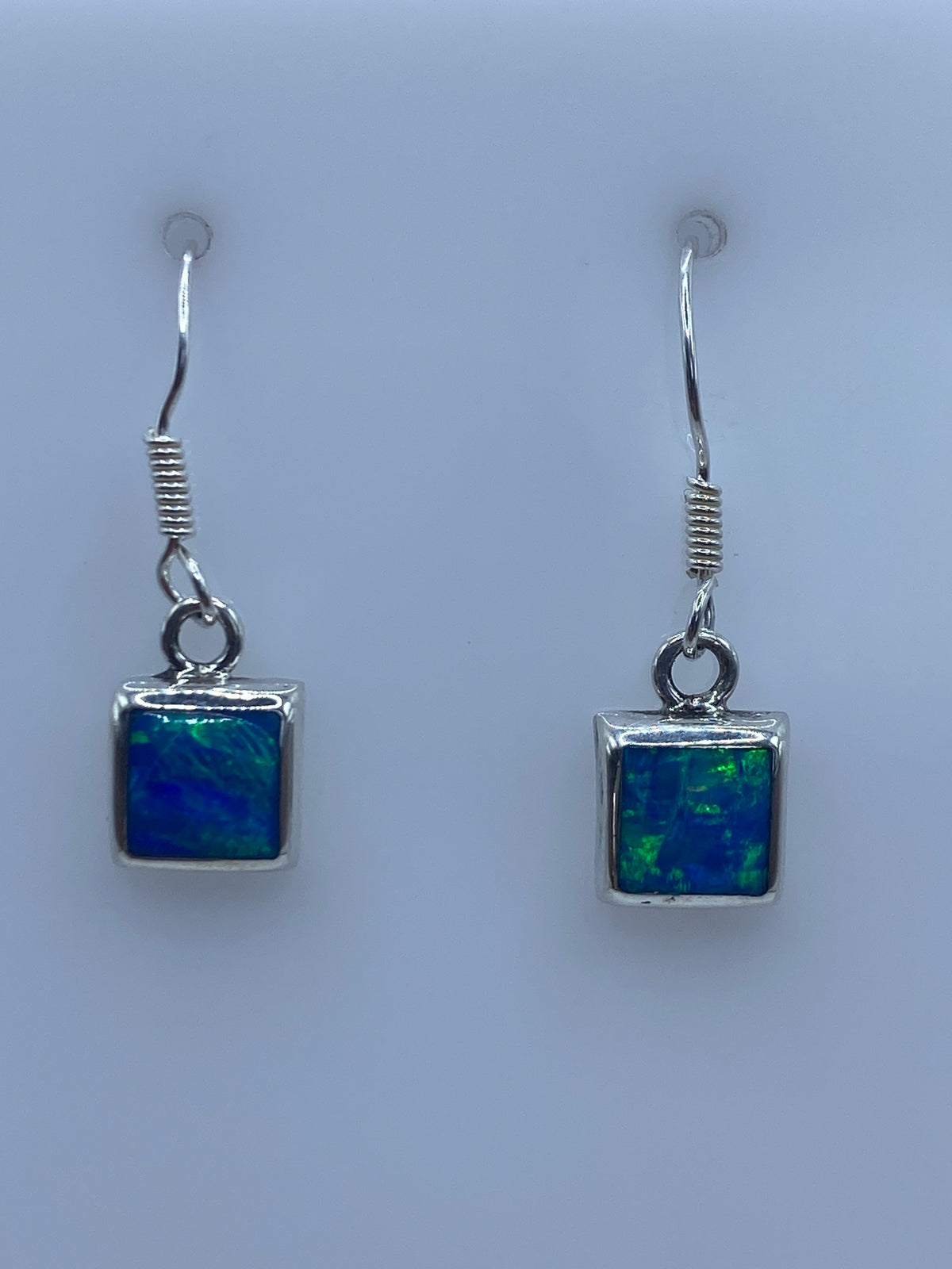 Detalle de uno de los aretes mostrando el engaste a mano y el ópalo azul