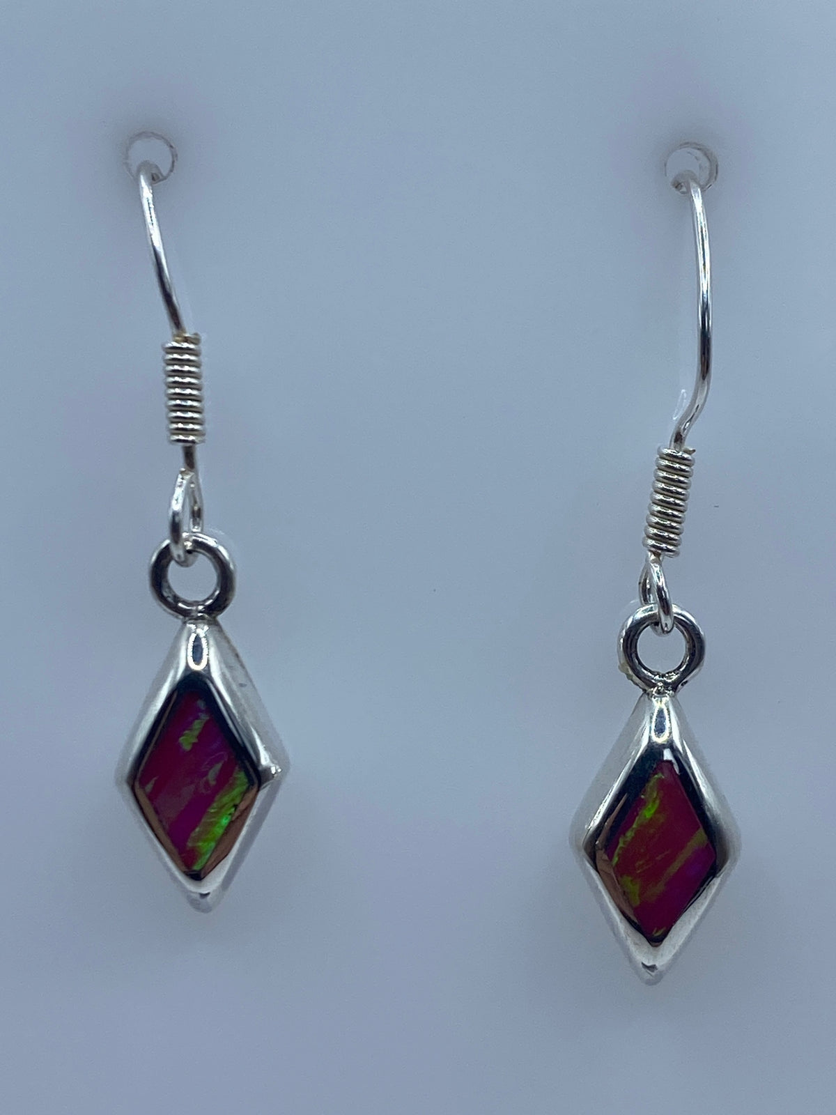 Aretes de plata con Opalo de Fuego rosa colgando en vista frontal