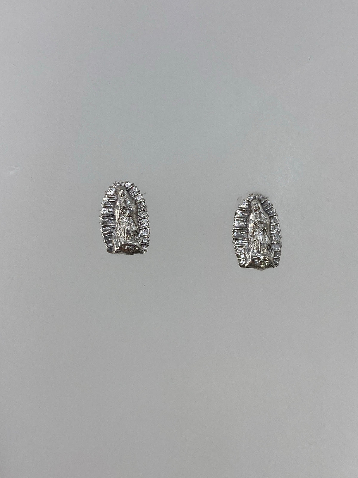Detalle frontal de aretin de plata con Virgen rodeada de rayos