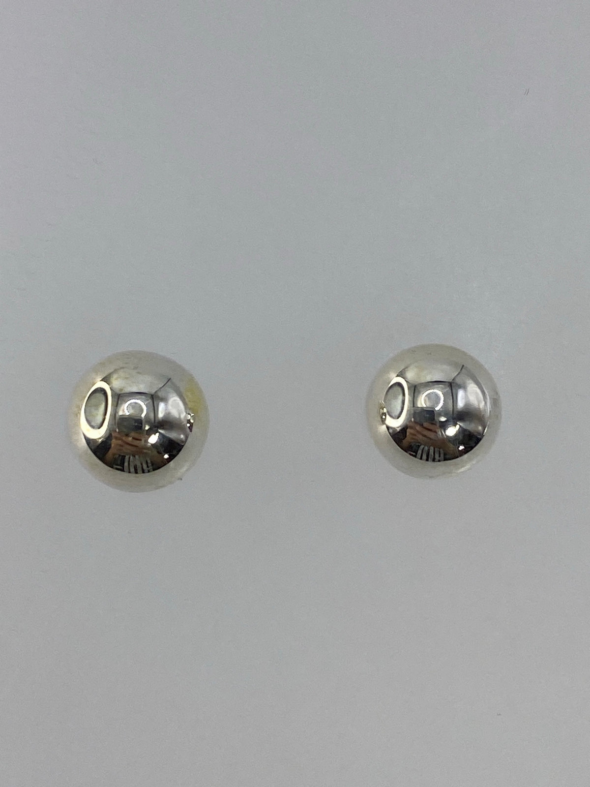 Aretes de plata 925 en cartoneado, esferas pulidas minimalistas, vistos desde el frente