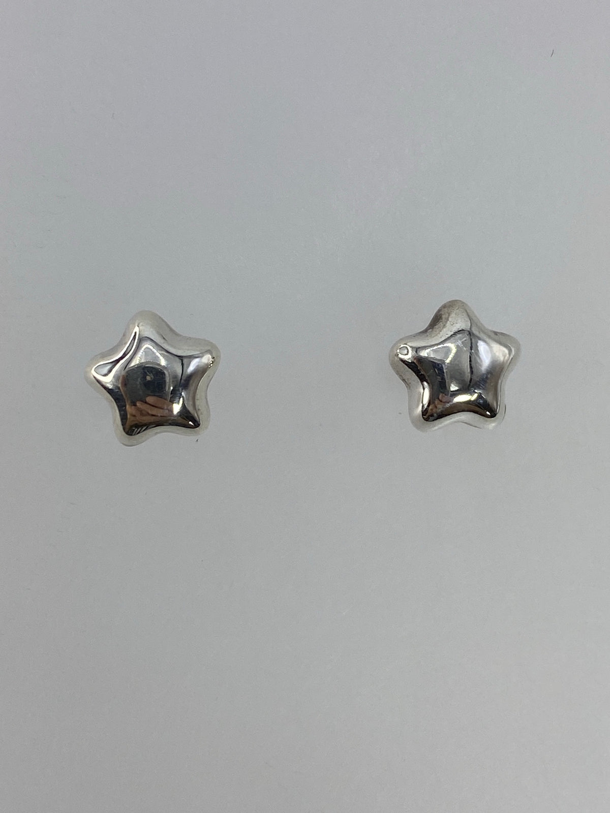 Par de aretes de plata cartoneado en forma de estrella, vista frontal del volumen 3D