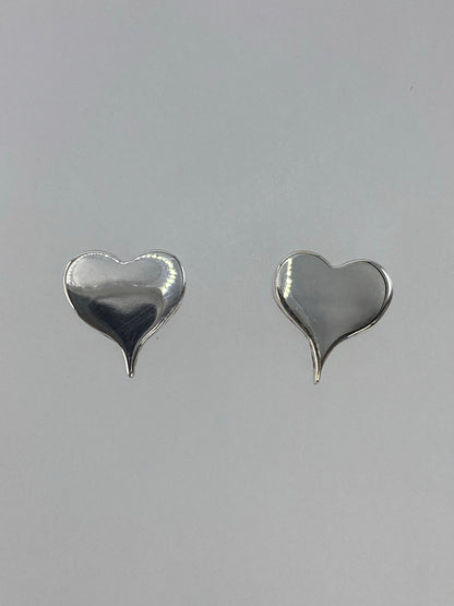 Aretes de plata corazón cartoneado en posición frontal, par completo