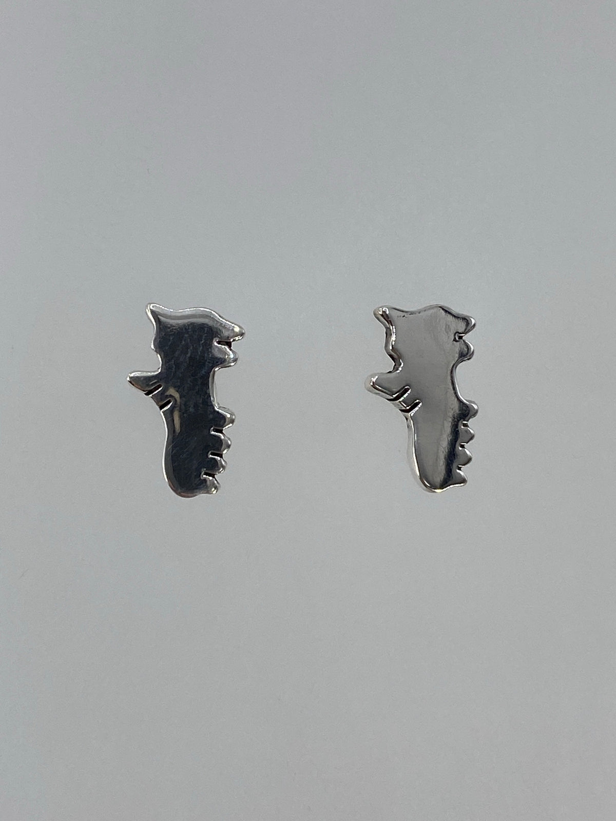 Detalle frontal de los aretes mostrando la técnica de cartoneado y pulido espejo
