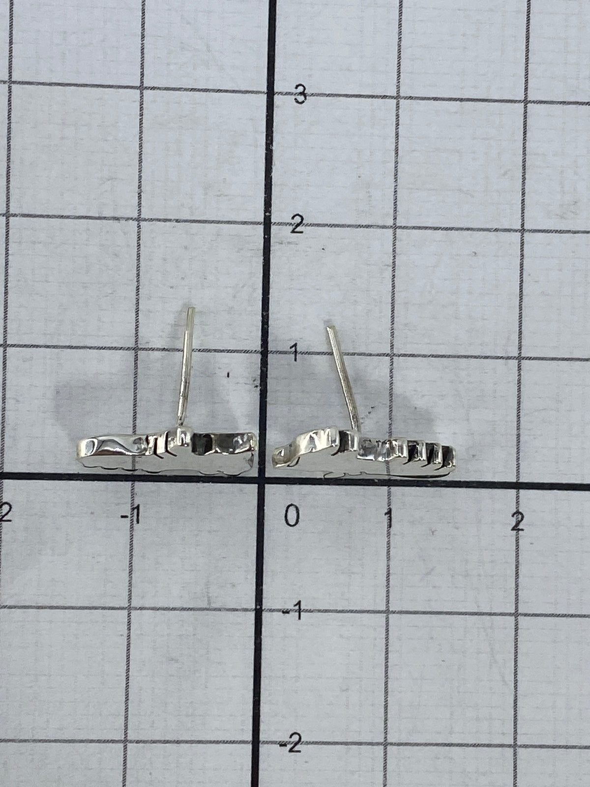 Aretes de plata con luz reflejando el acabado pulido y el Quinto 925