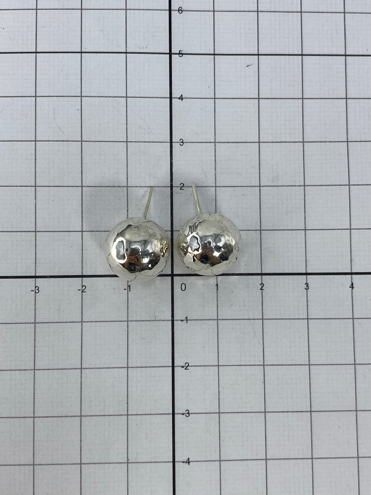Aretes sobre fondo blanco mostrando la forma perfecta y el brillo de la plata 925