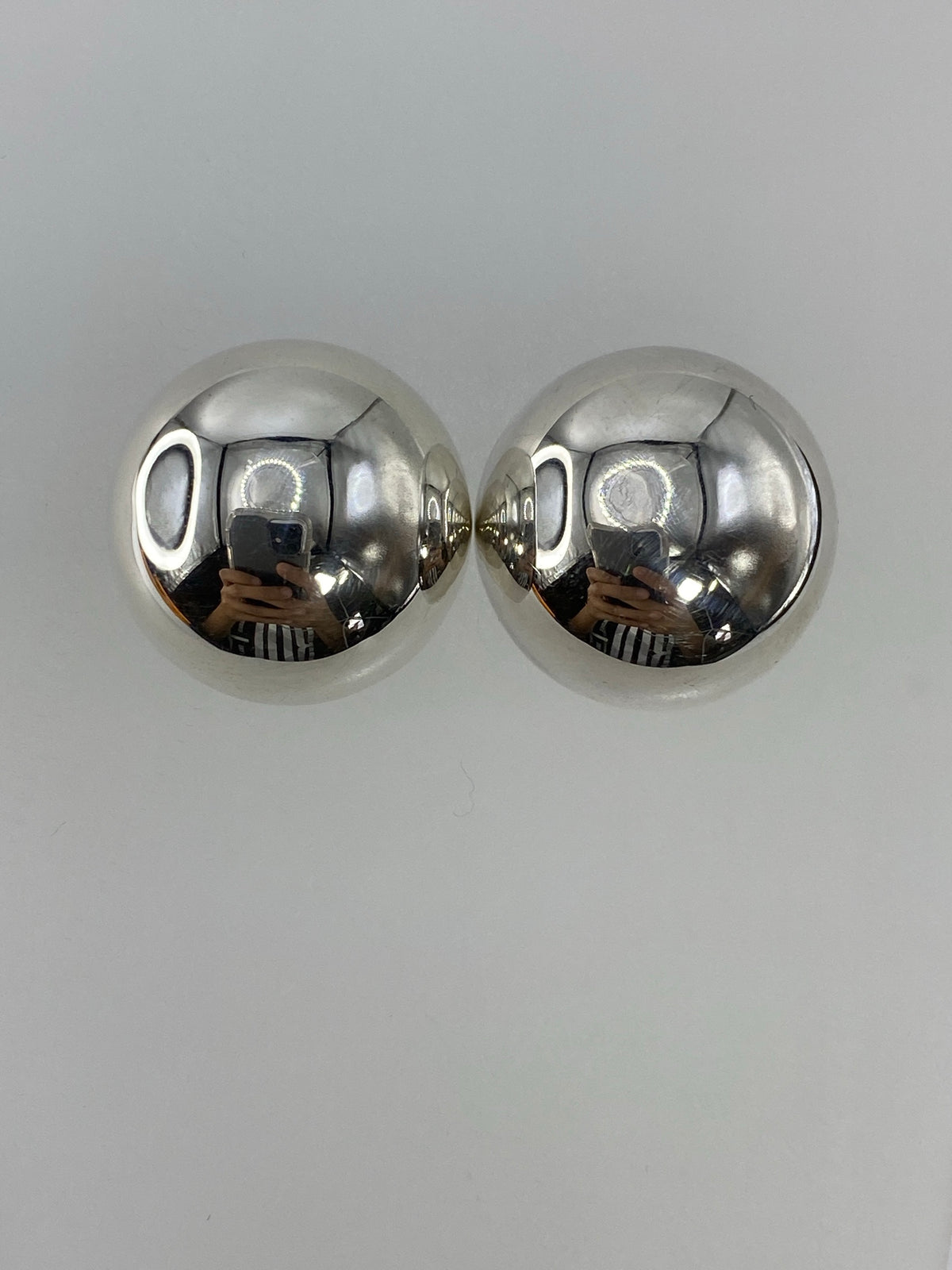 Aretes de plata cartoneado vistos de frente sobre fondo gris
