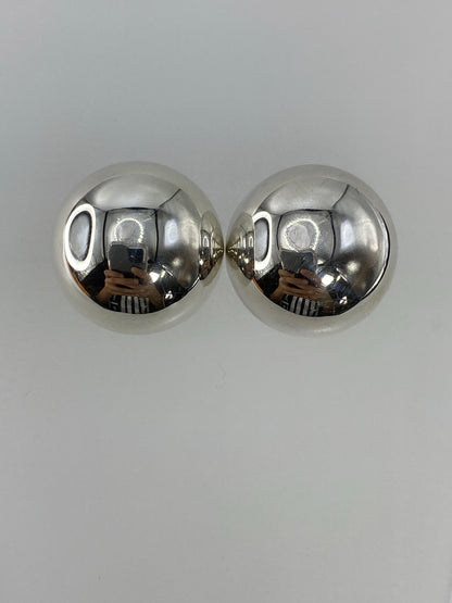 Aretes de plata cartoneado vistos de frente sobre fondo gris