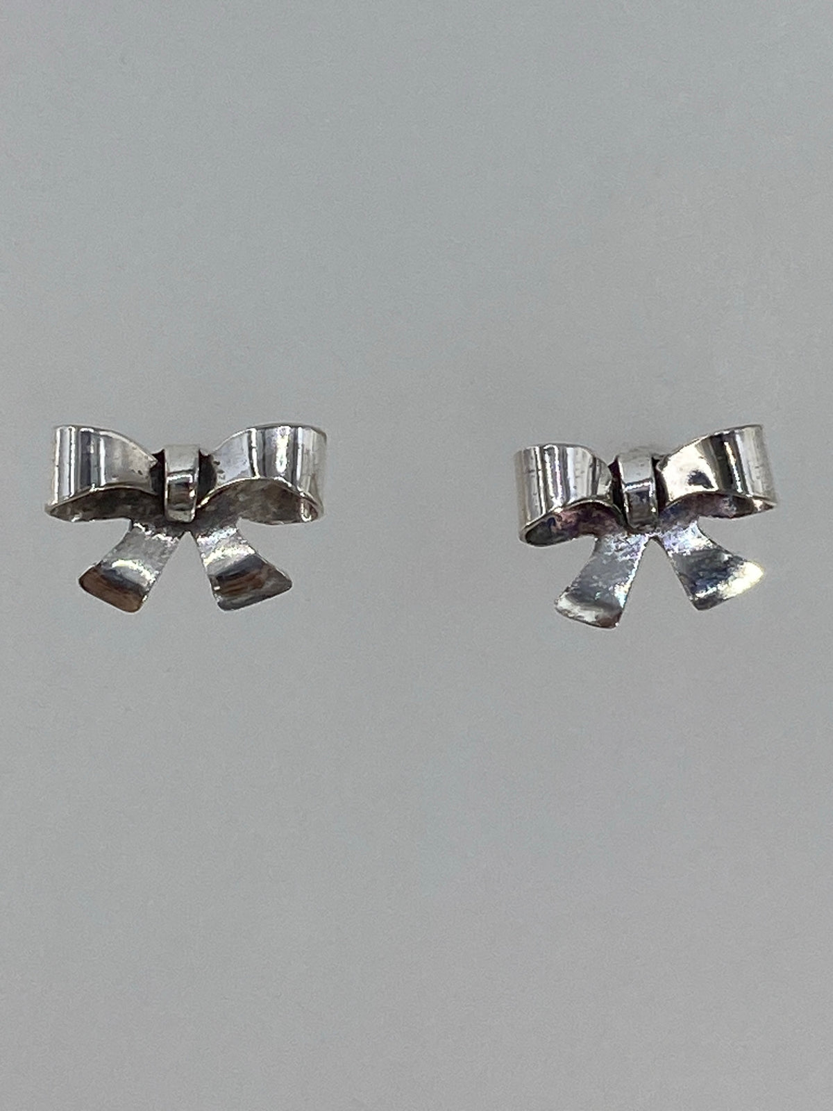 Aretes minimalistas de plata con cierre de espiga, sobre fondo blanco
