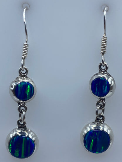Vista lateral de los aretes mostrando el tono azul profundo del Ópalo de Fuego