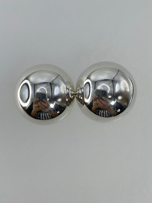 Par de aretes de plata cartoneado, esféricos y brillantes, sobre fondo blanco
