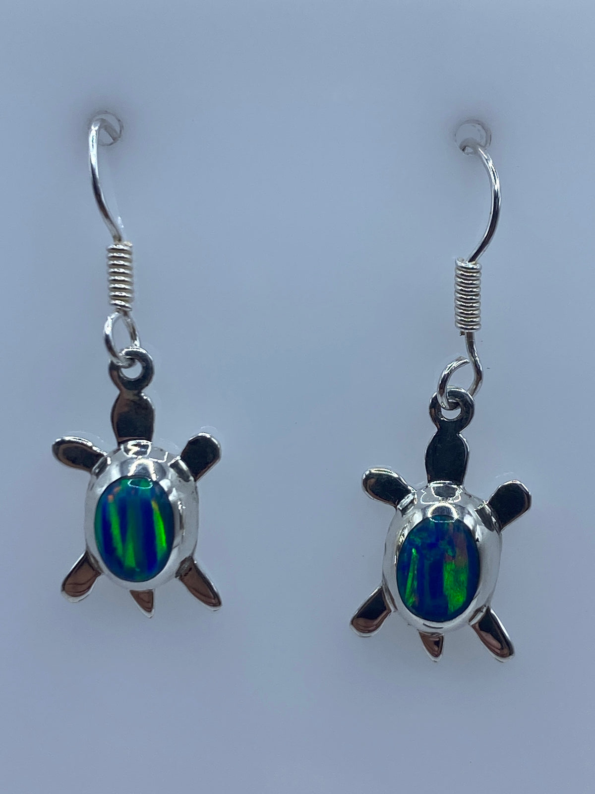 Par de aretes de plata con ópalo de fuego azul en forma de tortuga, colgando de los ganchos