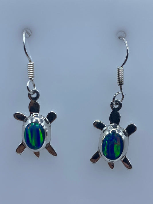 Par de aretes de plata con ópalo de fuego azul en forma de tortuga, colgando de los ganchos