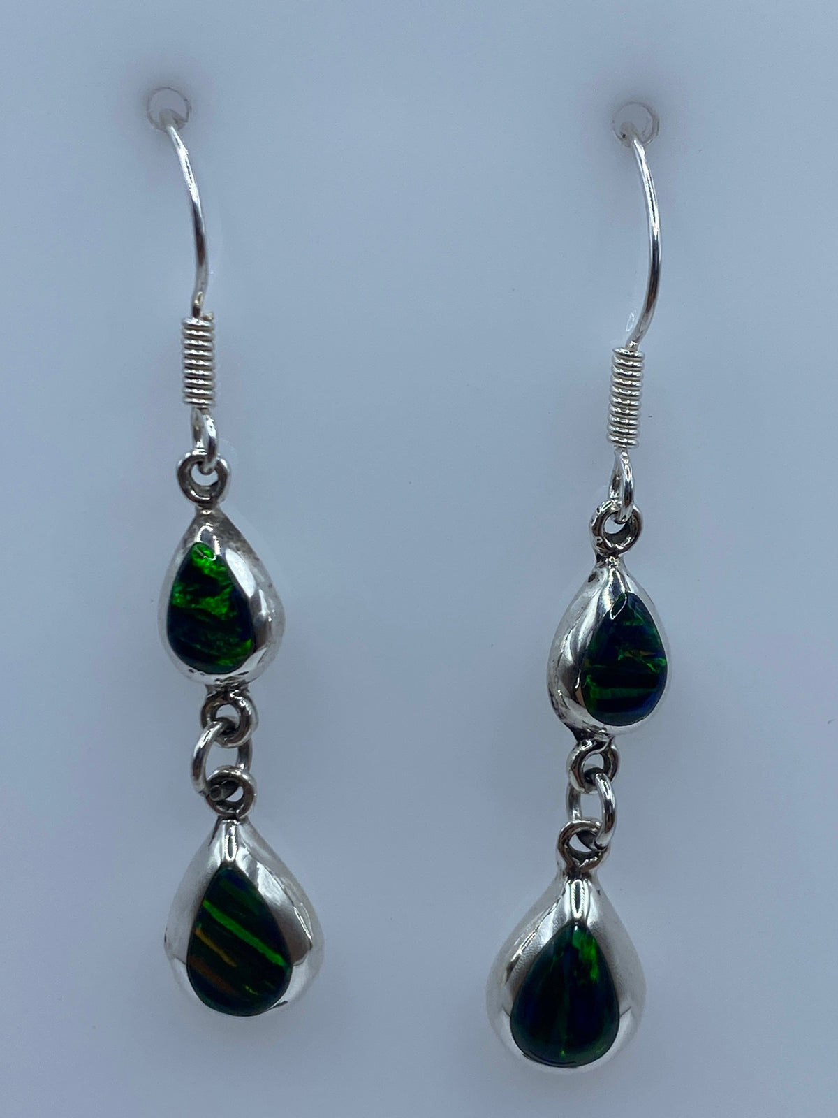 Detalle del ópalo de fuego verde engastado en plata, mostrando reflejos luminosos