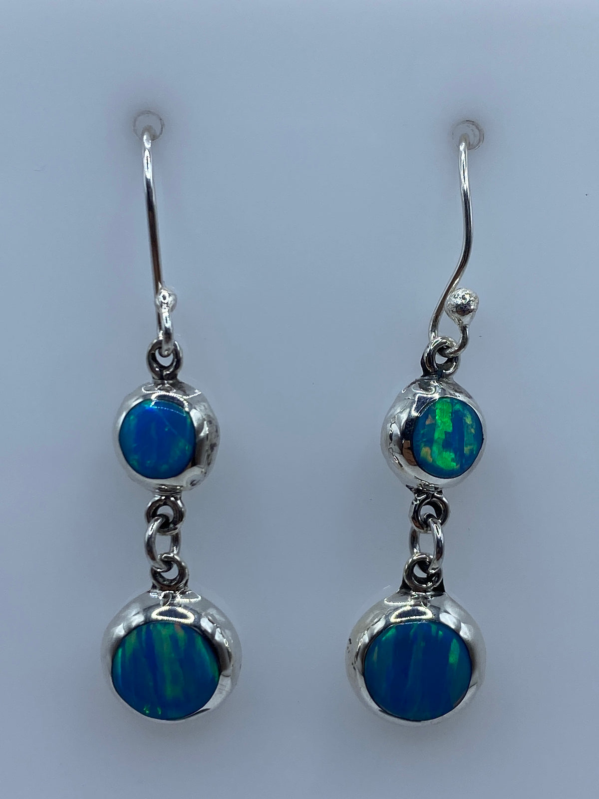 Par de aretes de plata con ópalo de fuego azul cielo colgando hacia adelante