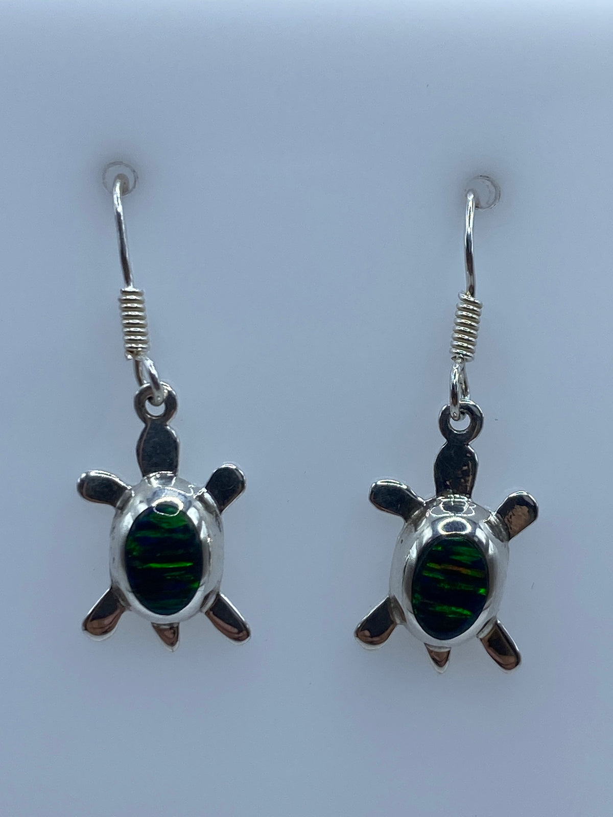 Detalle del opalo de fuego engastado en la tortuga de plata, mostrando los colores verdes y dorados