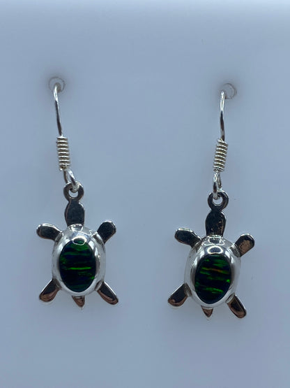 Detalle del opalo de fuego engastado en la tortuga de plata, mostrando los colores verdes y dorados