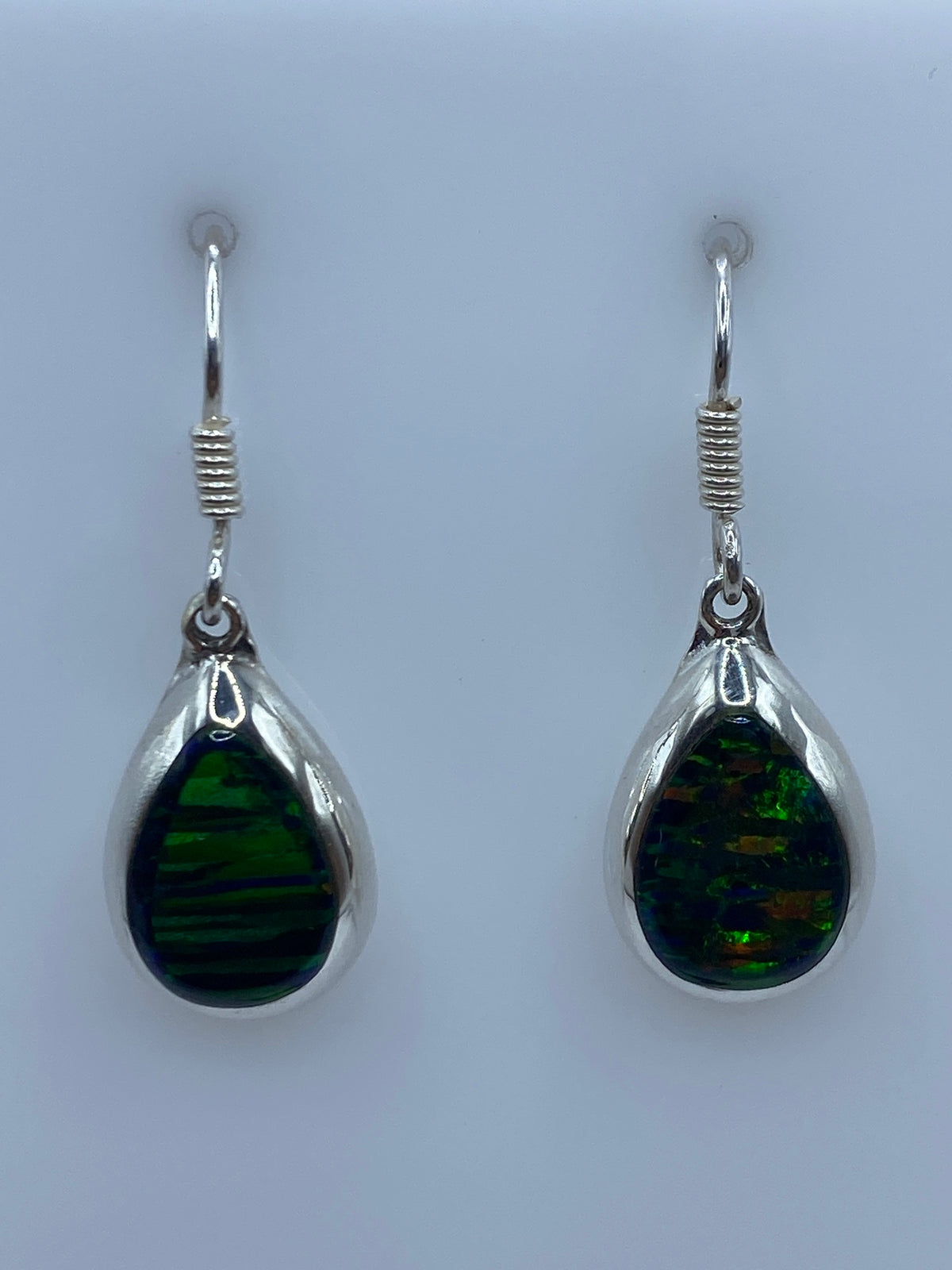 Detalle frontal de los aretes mostrando el Ópalo de Fuego con reflejos dorados y azulados