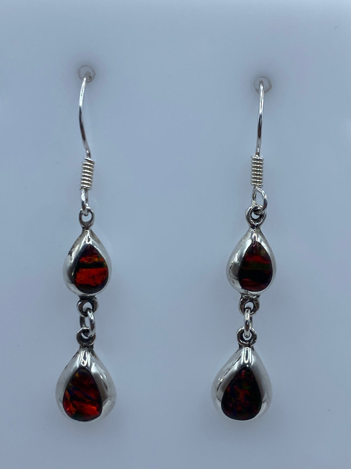 Par de aretes mostrando el opalo de fuego con reflejos rojos y anaranjados