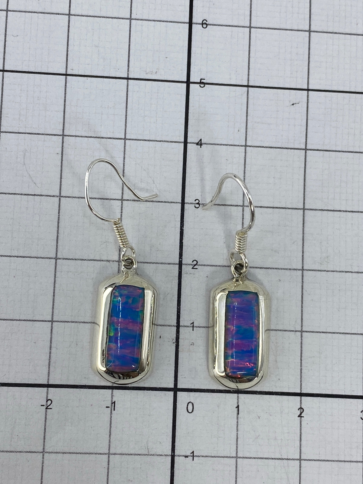 Aretes sobre regla de medición mostrando largo de 3 cm