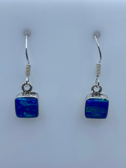 Detalle de arete individual mostrando el Ópalo de Fuego azul y el engaste a mano en plata 950