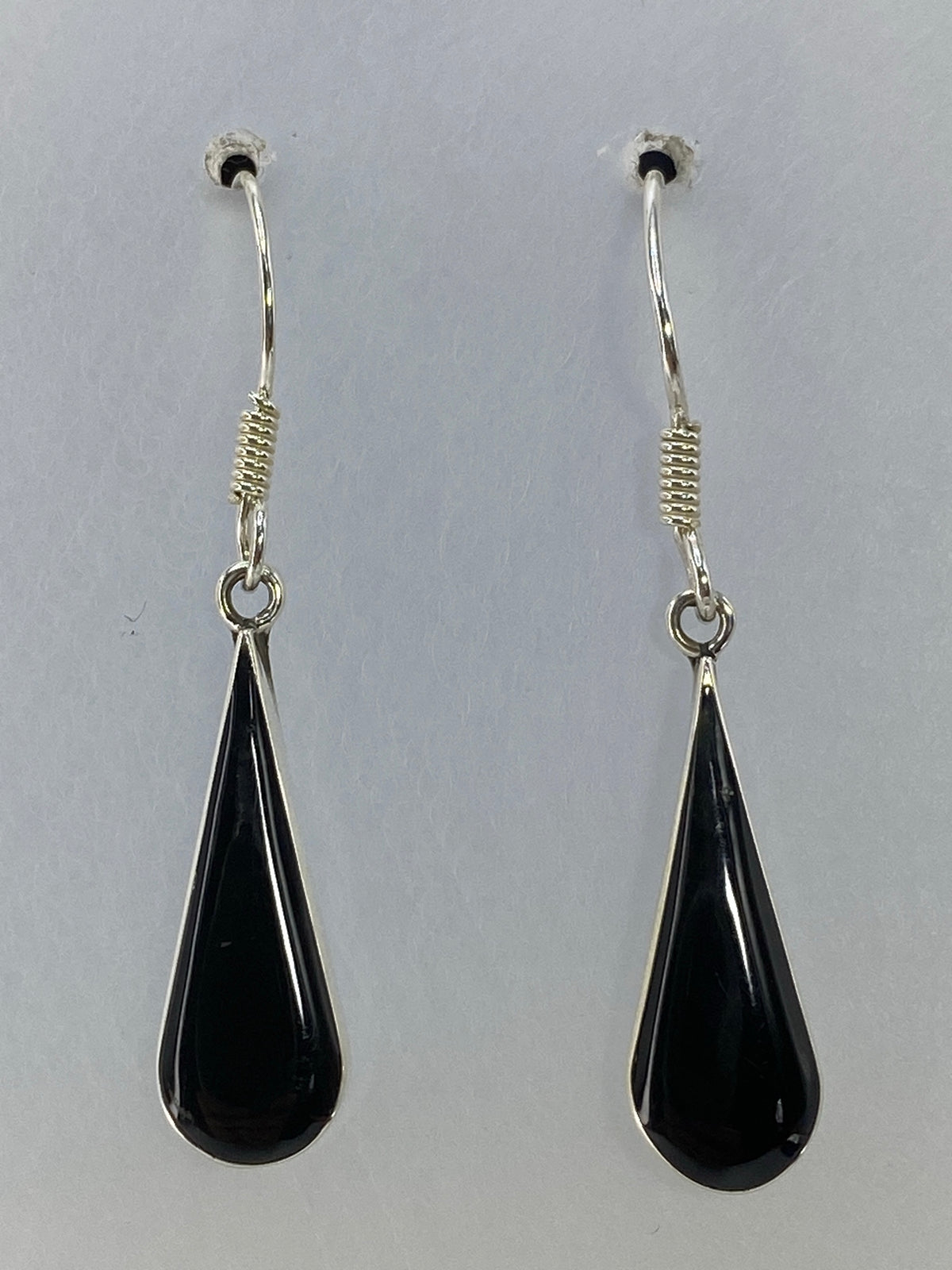 Aretes de plata 925 con onix negro de 3 cm de largo, colgando sobre fondo gris