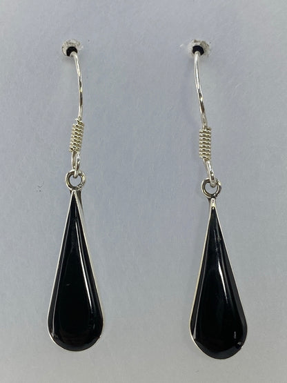 Aretes de plata 925 con onix negro de 3 cm de largo, colgando sobre fondo gris