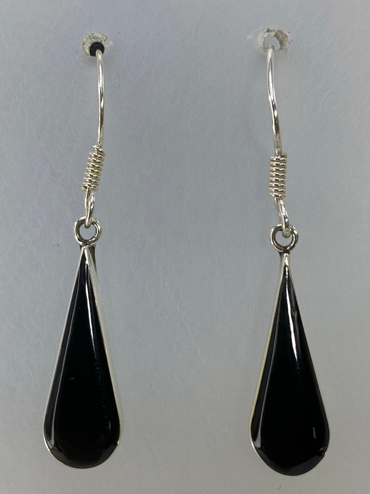 Par de aretes de onix negro vistos con regla de centímetros para escala