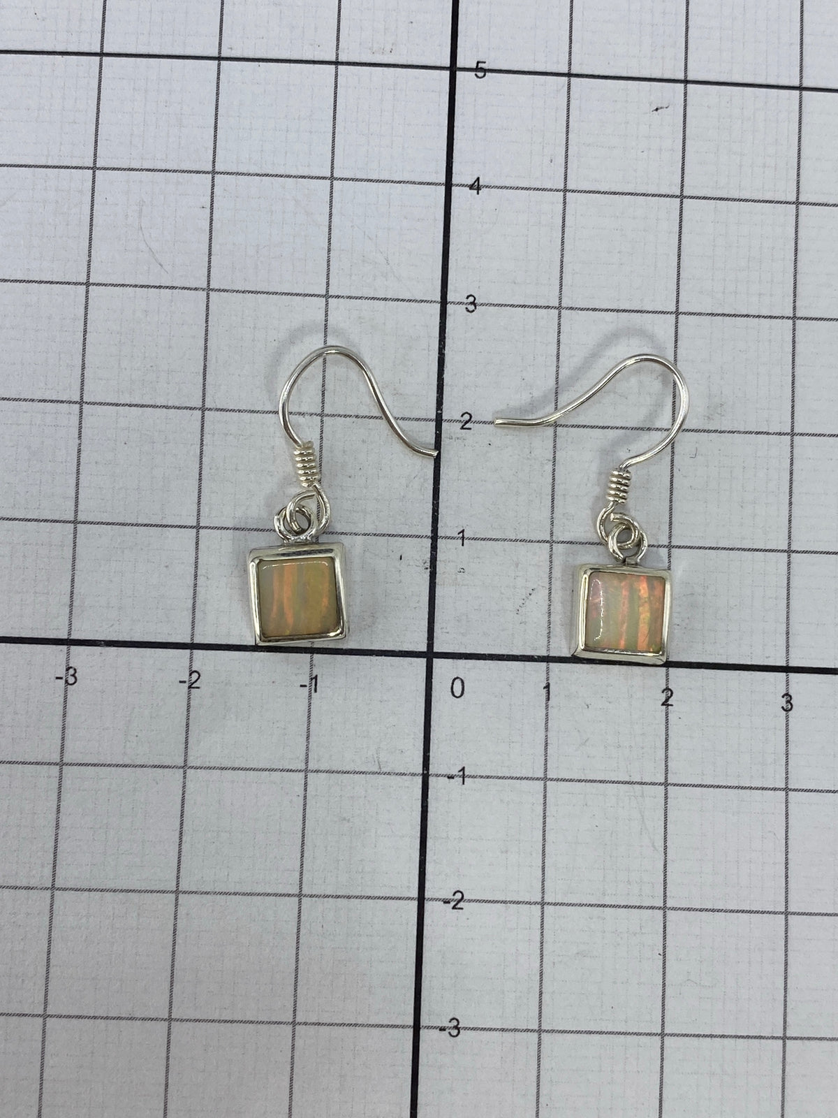 Aretes de opalo de fuego sobre fondo neutro, vista de frente del par