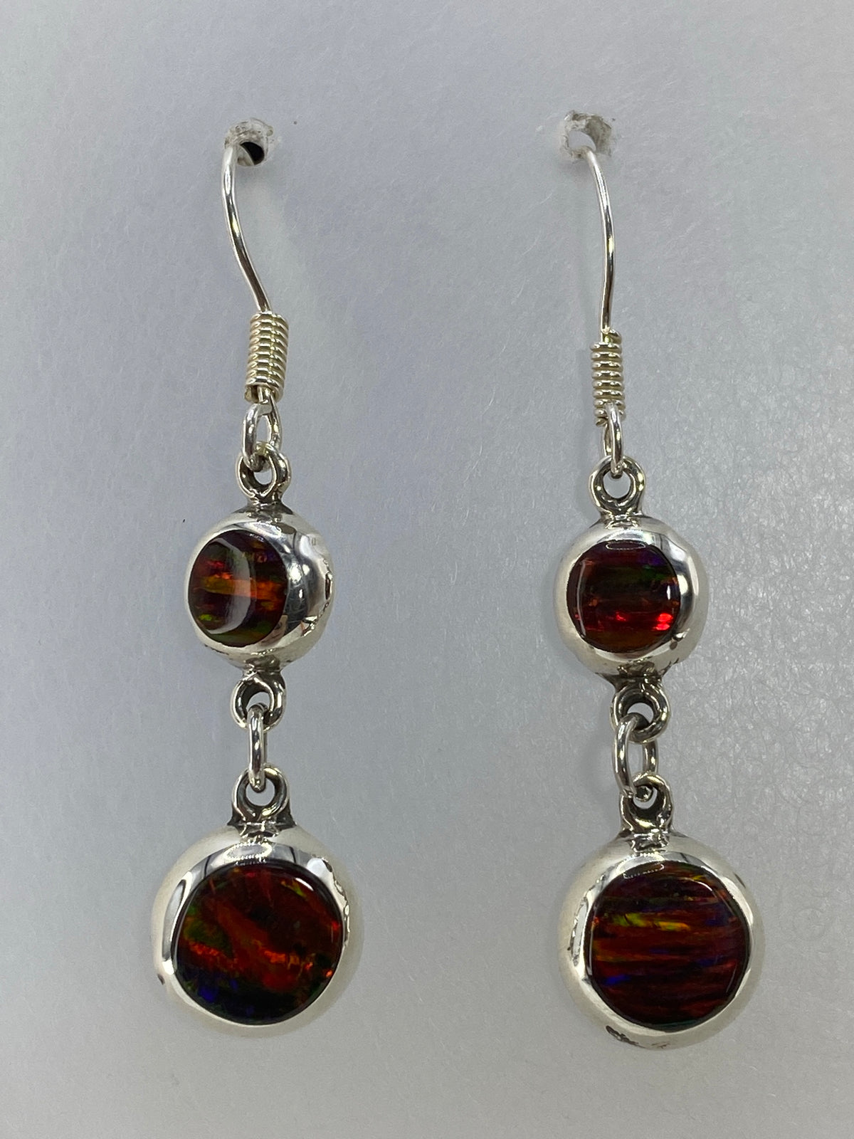 Par de aretes de plata 925 con Ópalo de Fuego rojo engastado, colgando sobre fondo blanco