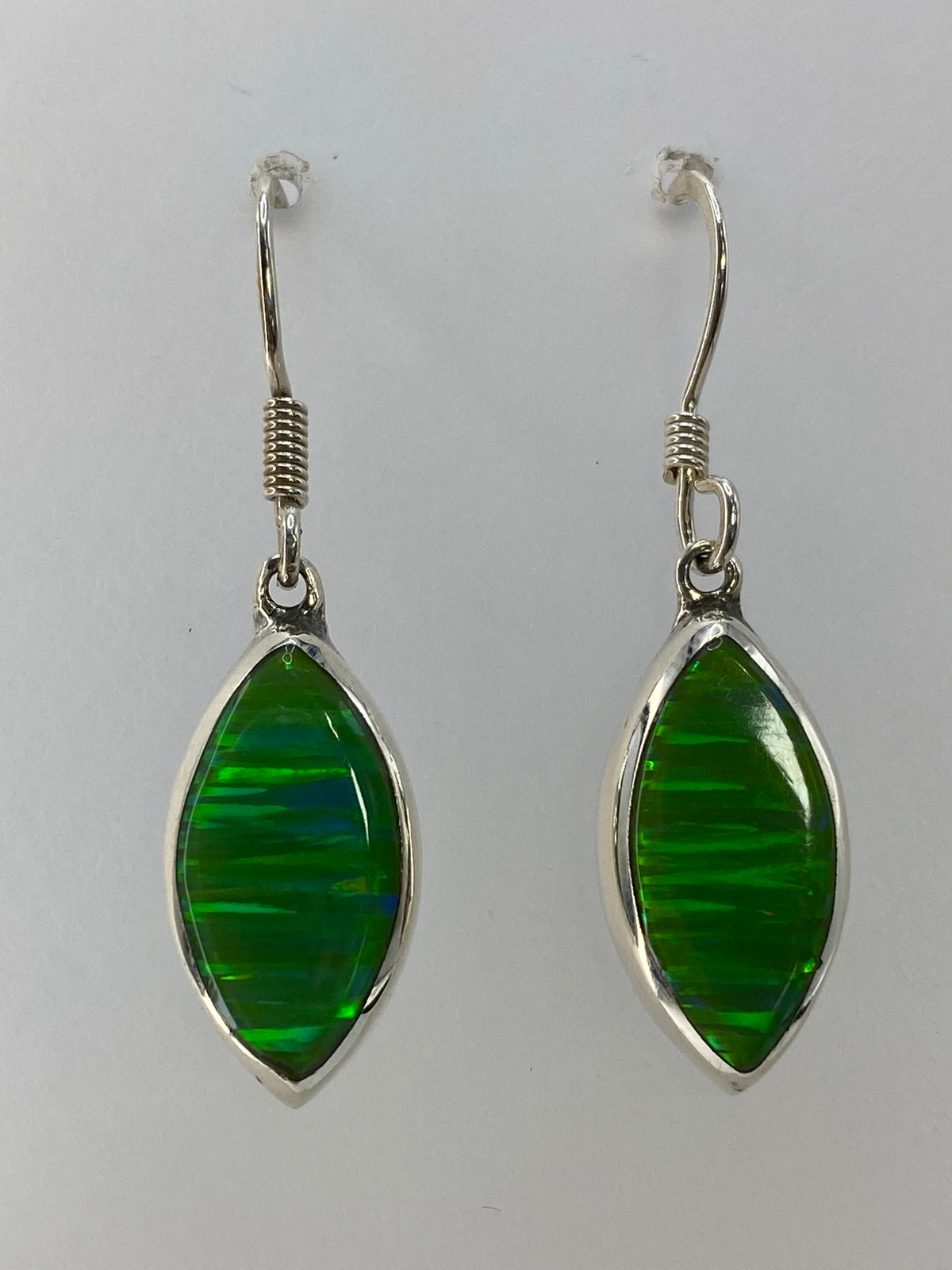 Par de aretes de plata 925 con ópalo de fuego verde limón, colgando sobre fondo blanco