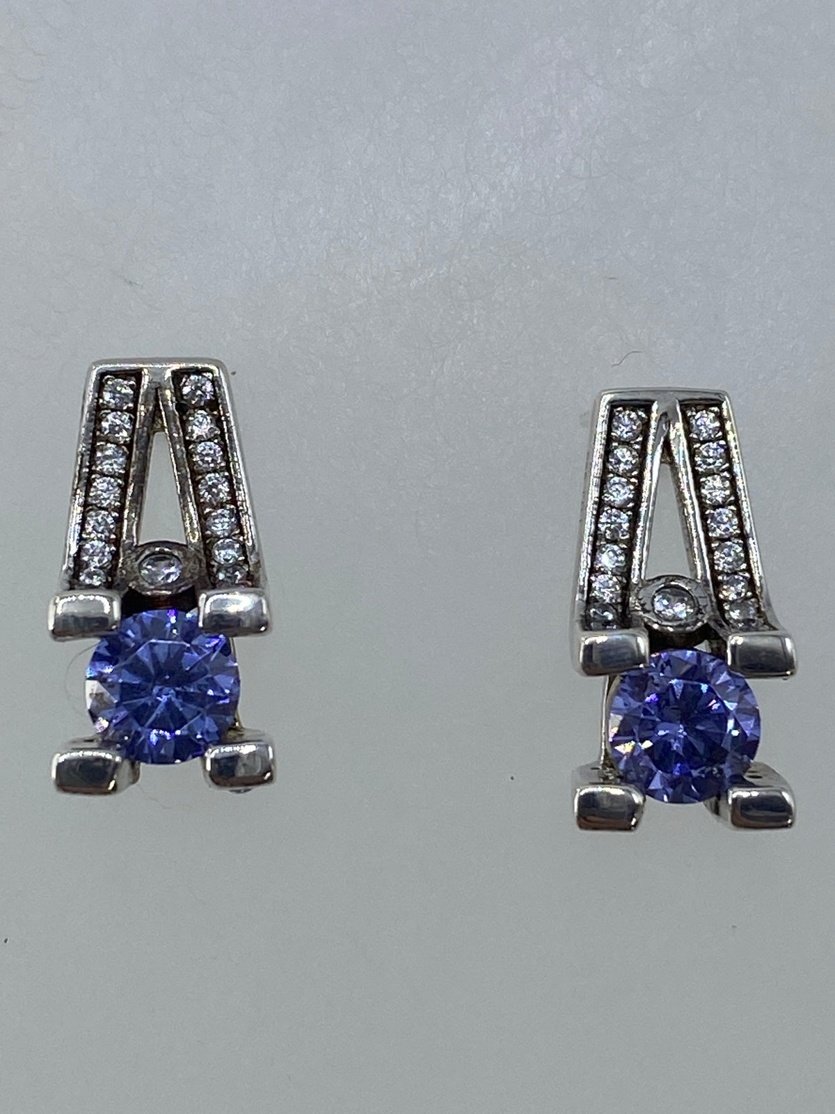 Aretes de plata 925 con circonia morada en vista lateral sobre fondo blanco