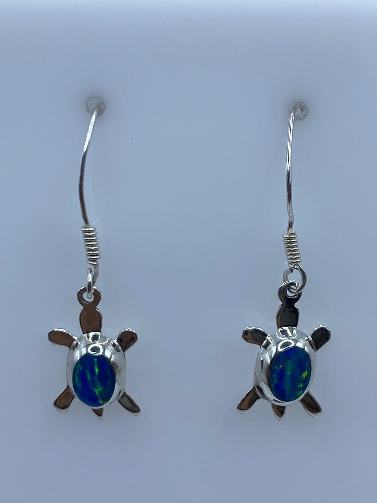 Detalle frontal de los aretes mostrando el Ópalo de Fuego azul engastado en plata 925