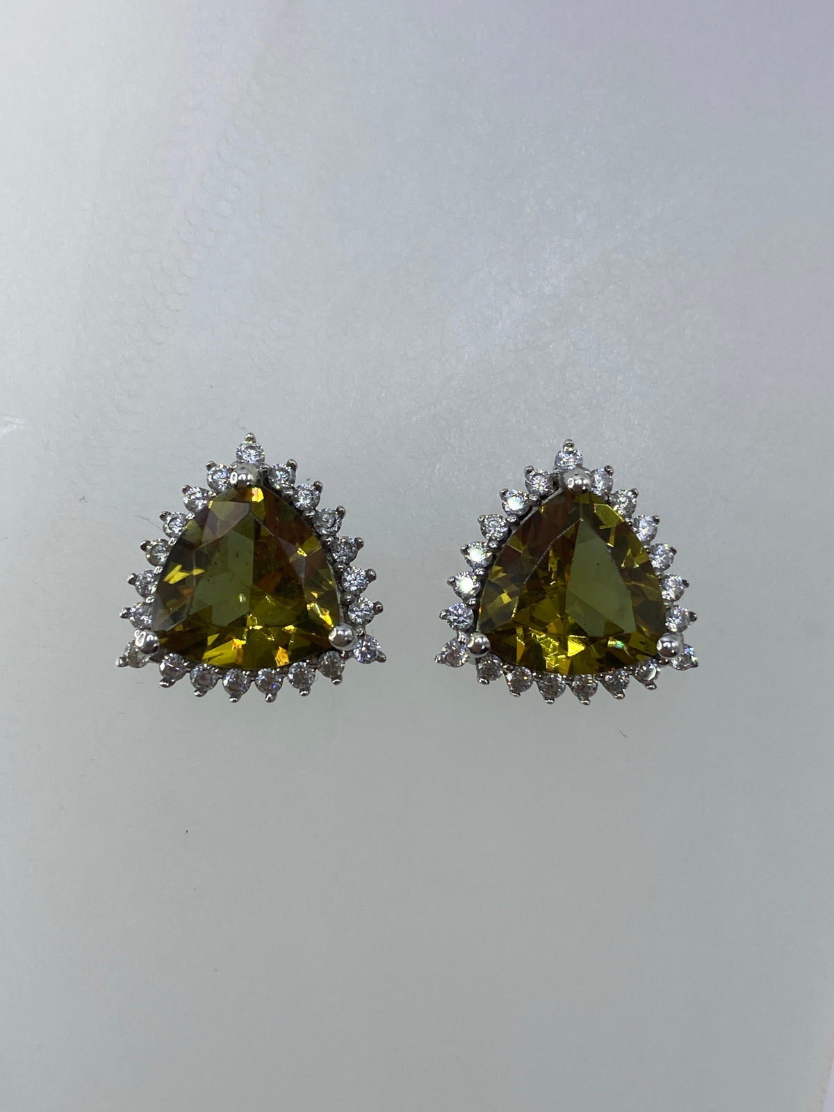 Detalle frontal de los aretes mostrando el engaste de circonia verde olivo