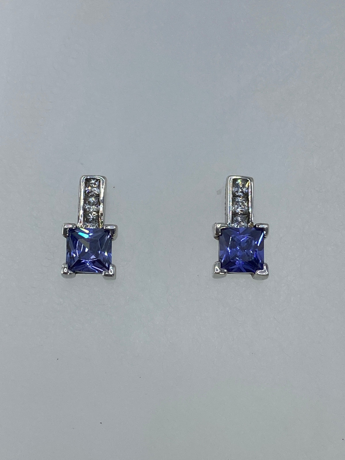 Detalle frontal de los aretes mostrando la circonia azul y el brillo de la plata
