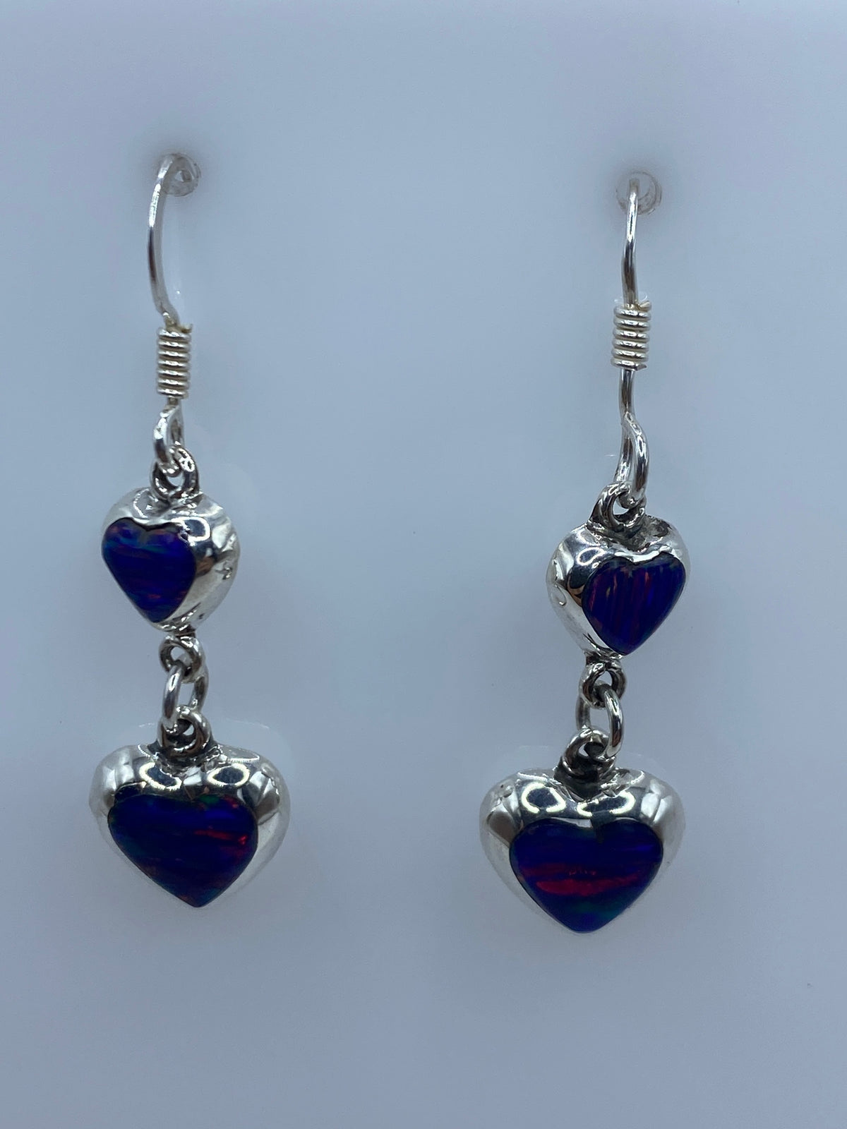 Aretes colgando mostrando el brillo del ópalo azul y los engastes de plata