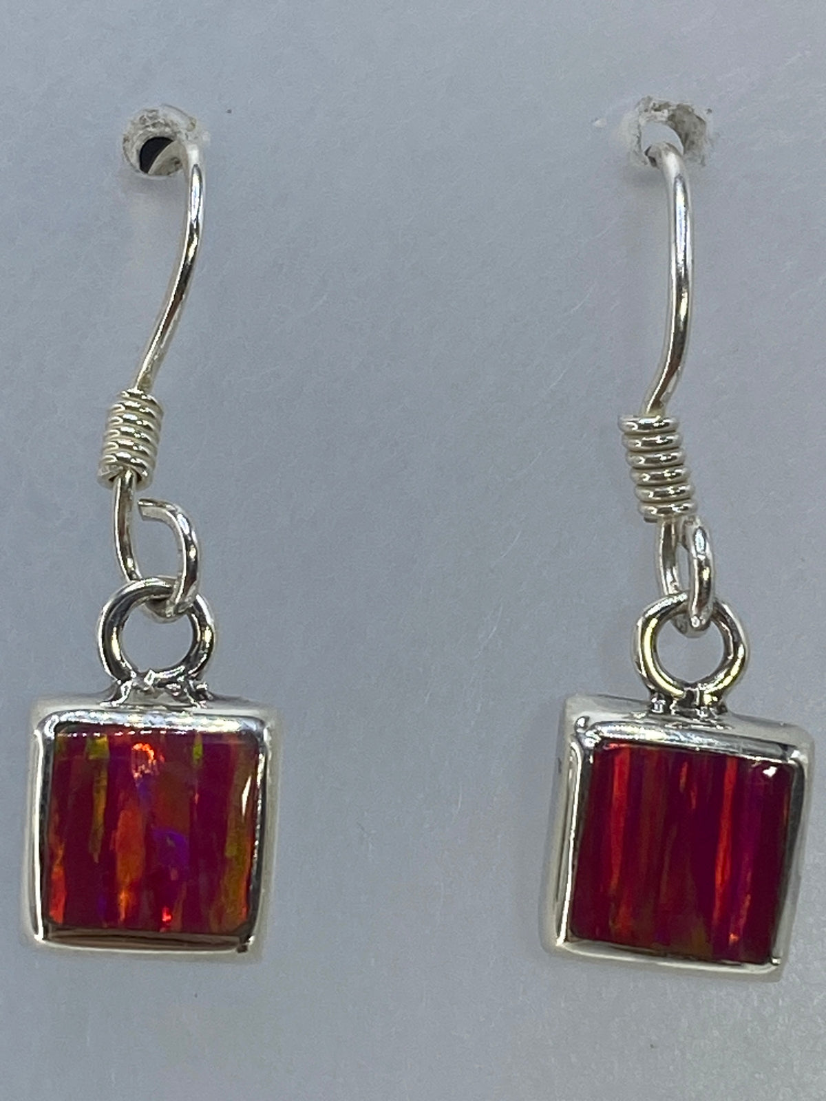 Aretes colgando mostrando el reflejo iridiscente del ópalo rosa
