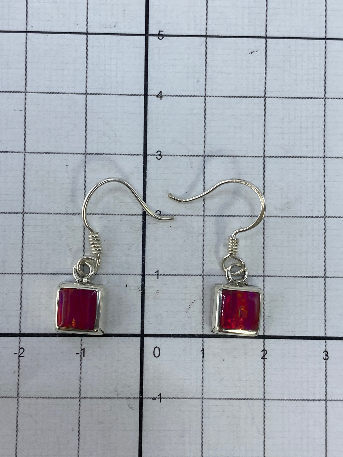 Aretes sobre fondo blanco con gancho de plata y Quinto visible