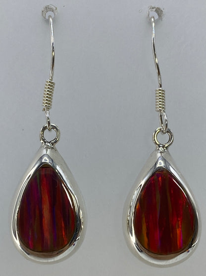 Aretes de ópalo de fuego en la oreja, brillando con luz natural