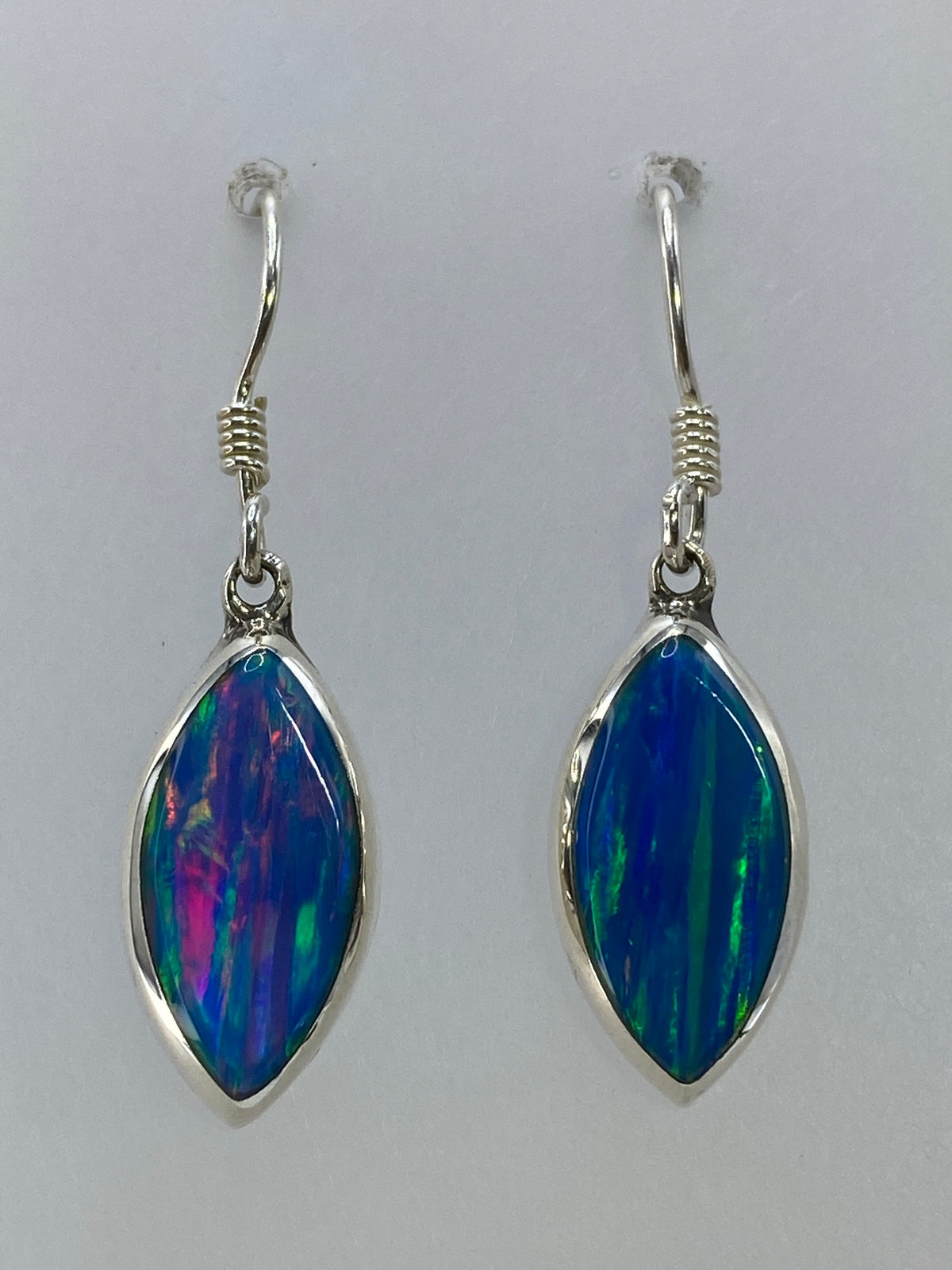 Par de aretes de plata con ópalo de fuego multicolor mostrando azul, verde y rojo