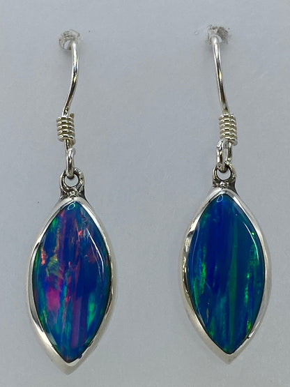 Aretes de ópalo de fuego en la mano mostrando el juego de colores a la luz