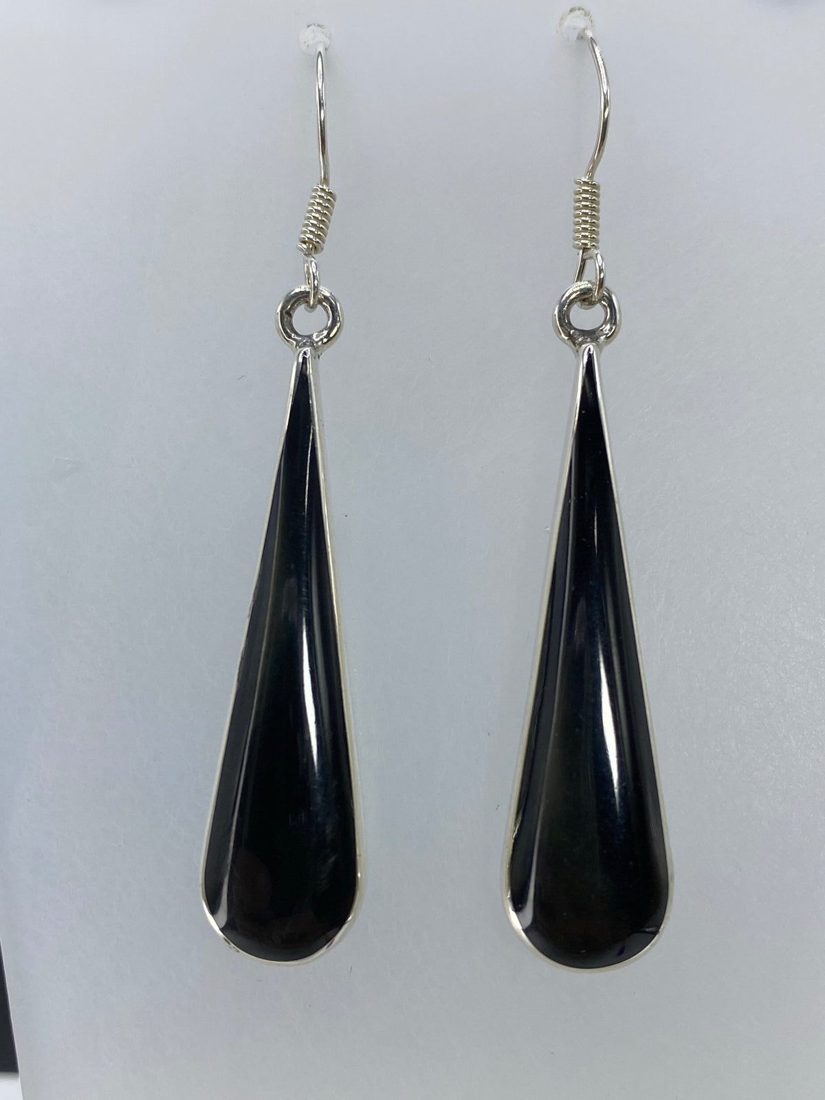Aretes largos con onix negro en detalle, mostrando el engaste a mano
