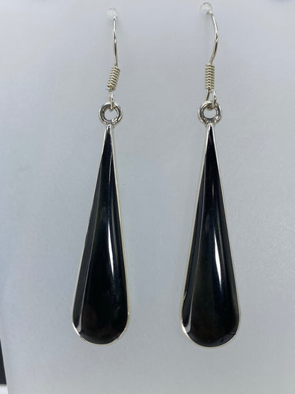Aretes largos con onix negro en detalle, mostrando el engaste a mano