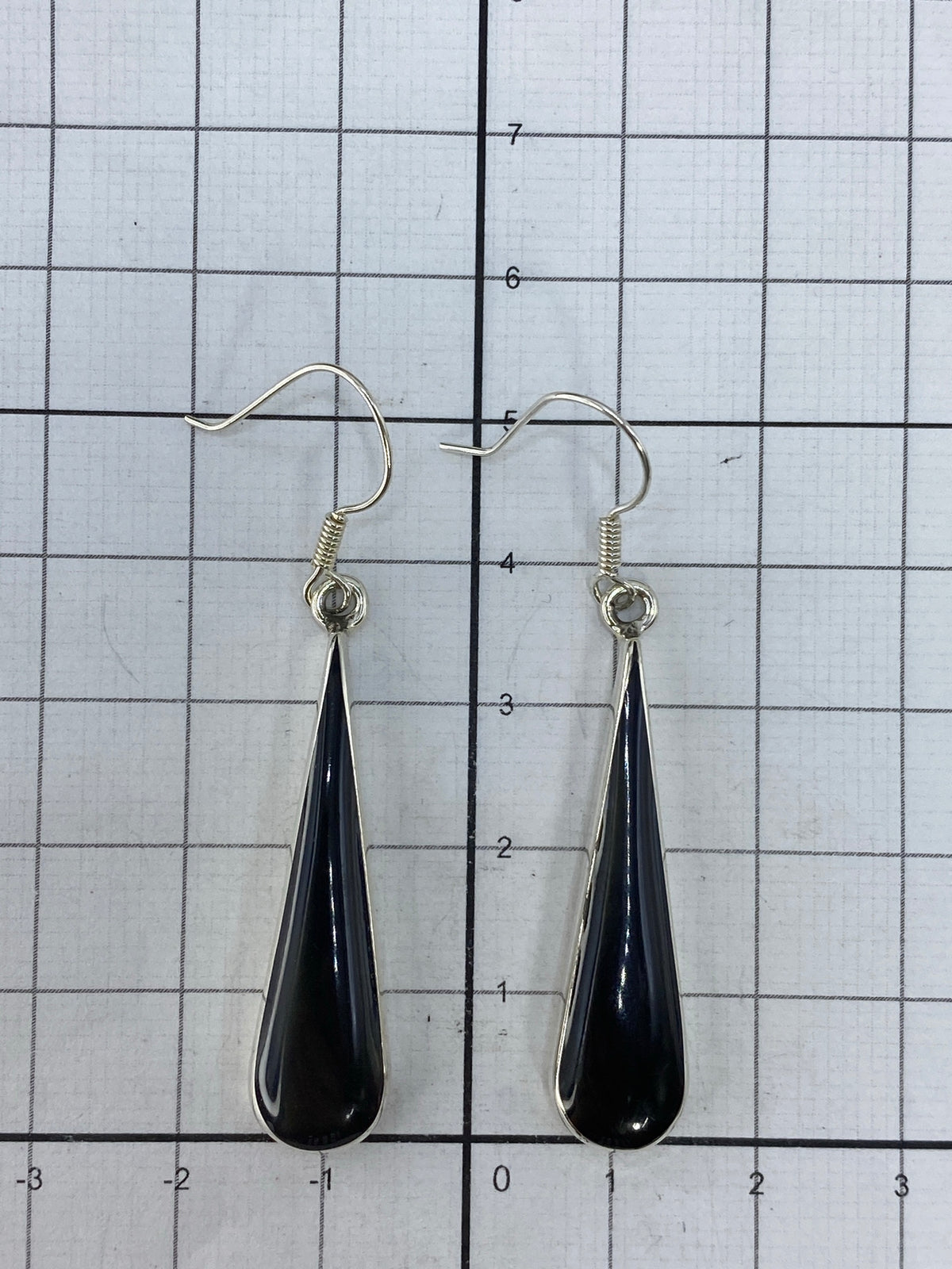 Aretes con onix en mano, mostrando proporción y brillo de la plata